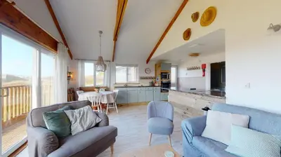 a living room with two couches and a kitchen at E48 Redville, Riviere Towans in Hayle