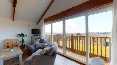 a living room with a couch and a large window at E48 Redville, Riviere Towans in Hayle