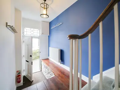 a blue wall in a hallway with a staircase at Church Hill House in Port Isaac