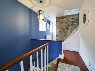 a staircase with blue walls and a stone wall at Church Hill House in Port Isaac