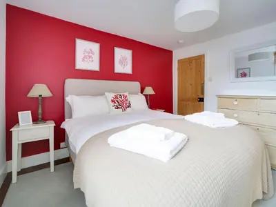 two beds in a bedroom with red walls at Church Hill House in Port Isaac