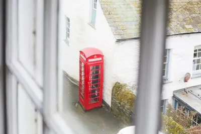 a red phone booth sitting in the side of a building at Church Hill House in Port Isaac