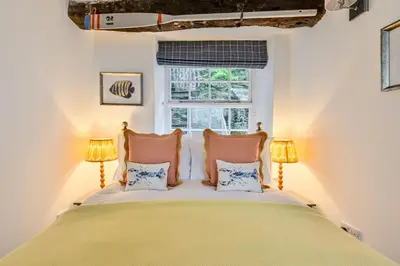 a bedroom with a bed with two pillows and a window at Old Cobblers in Port Isaac