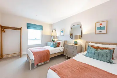 a bedroom with two beds and two mirrors at Porth Beach Villa in Newquay