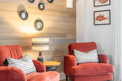 a living room with two chairs and a table at Porth Beach Villa in Newquay