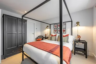 a bedroom with a black canopy bed with an orange blanket at Porth Beach Villa in Newquay