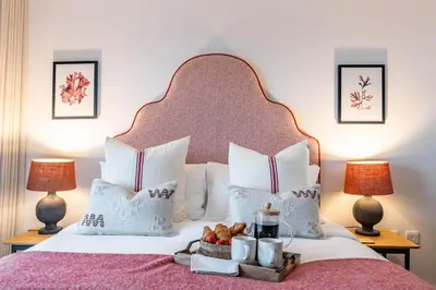 a hotel room with a bed with a tray of food on it at Porth Beach Villa in Newquay