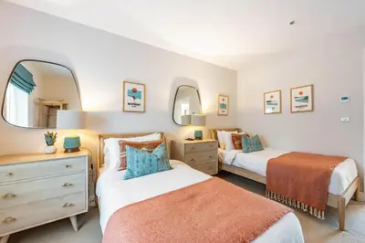two beds in a bedroom with two mirrors at Porth Beach Villa in Newquay
