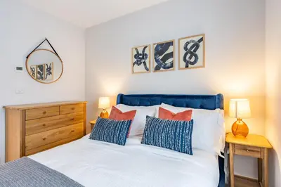 a bedroom with a bed with a blue headboard and pillows at Porth Beach Villa in Newquay