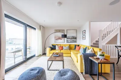 a living room with a yellow couch and a table at Porth Beach Villa in Newquay