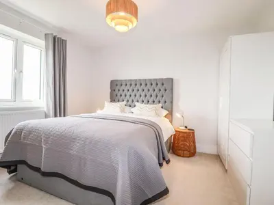a bedroom with a large bed with a gray headboard at Lavender House in Newquay