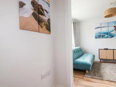 a living room with a blue couch and paintings on the wall at Lavender House in Newquay