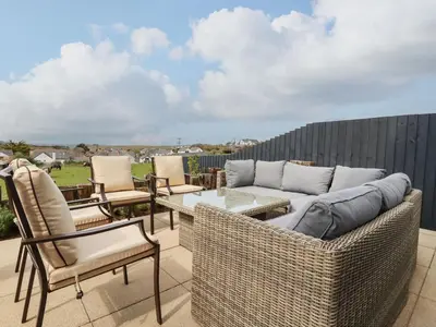 a patio with wicker chairs and a couch and a table at Lavender House in Newquay