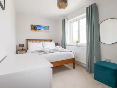 a white bedroom with two beds and a window at Lavender House in Newquay