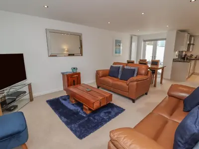 a living room with leather furniture and a flat screen tv at Moonsail in Carbis Bay