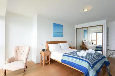 a bedroom with a bed and a chair and a mirror at Glas Mor in Carbis Bay