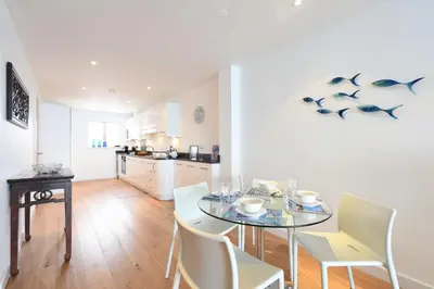 a dining room with a table and chairs and a kitchen at Glas Mor in Carbis Bay