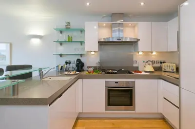 a kitchen with white cabinets and stainless steel appliances at The Waves in St Ives