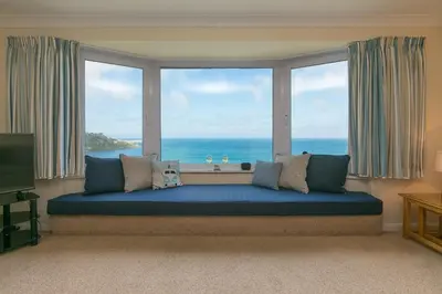 a large window with a large blue couch in a room at Dolphin Watch in Carbis Bay