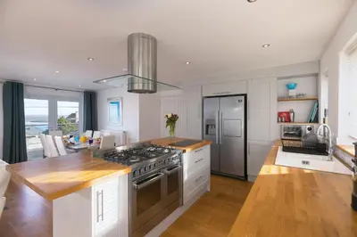 a kitchen with white cabinets and a stove top oven at Chy Lowen in Carbis Bay