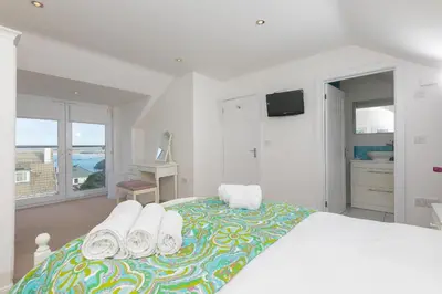 a white bedroom with a large bed with towels on it at Chy Lowen in Carbis Bay