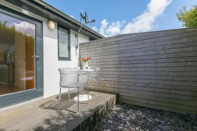 a chair sitting on a deck next to a wall at Gwel An Chapel in Carbis Bay