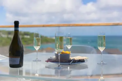 a glass table with a bottle of wine and three wine glasses at Gwel An Chapel in Carbis Bay