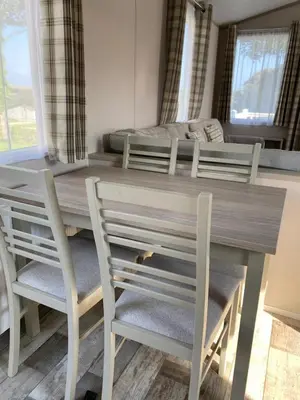 a dining room table with four chairs and a bed at Luxury Holiday Home Sleeps 6 Pet Friendly in St Austell