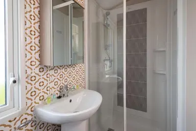 a bathroom with a sink and a mirror and a shower at Luxury Holiday Home Sleeps 6 Pet Friendly in St Austell