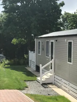 a small gray shed with a porch and a yard at Luxury Holiday Home Sleeps 6 Pet Friendly in St Austell