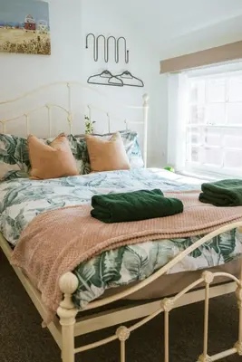 a bedroom with a bed with green sheets and a window at Breathtaking High Street Townhouse With Stunning Sea Views at 'The Old Fishermans Townhouse' in Falmouth