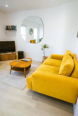 a yellow couch in a living room with a mirror at Breathtaking High Street Townhouse With Stunning Sea Views at 'The Old Fishermans Townhouse' in Falmouth
