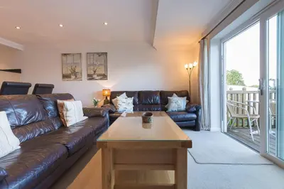 a living room with a leather couch and a table at Gennaker in Carbis Bay