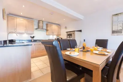 a kitchen with a wooden table with chairs and a dining room at Gennaker in Carbis Bay