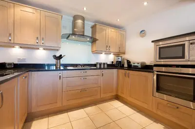 a kitchen with wooden cabinets and a stove top oven at Gennaker in Carbis Bay