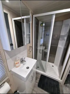 a white bathroom with a shower and a sink at Seven Sunsets, Padstow in Padstow