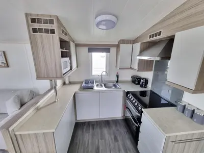 a small kitchen with white cabinets and a sink at Seven Sunsets, Padstow in Padstow