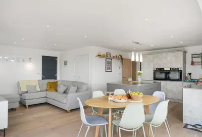 a kitchen and a living room with a table and chairs at Poppyfields in Germoe