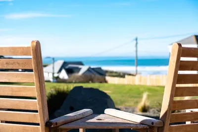 two wooden chairs sitting in front of the ocean at Blue Ridge in Wadebridge
