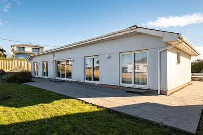 a white house with large windows in a yard at Blue Ridge in Wadebridge