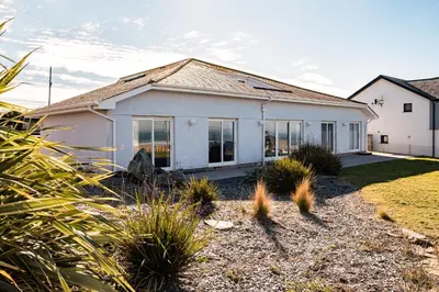a white house with large windows and plants at Blue Ridge in Wadebridge