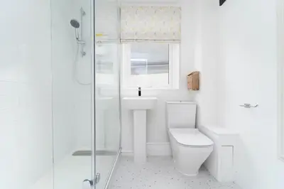 a white bathroom with a toilet and a shower at 8 Beach Court in St Ives