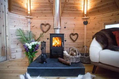 a living room with a fireplace in a log cabin at Romantic Treehouse with Hot Tub & BBQ Lodge in Praze an Beeble