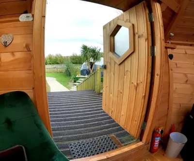 an open door of a wooden cabin with a porch at Romantic Treehouse with Hot Tub & BBQ Lodge in Praze an Beeble