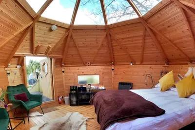 a bedroom with a large bed in a wooden room at Romantic Treehouse with Hot Tub & BBQ Lodge in Praze an Beeble