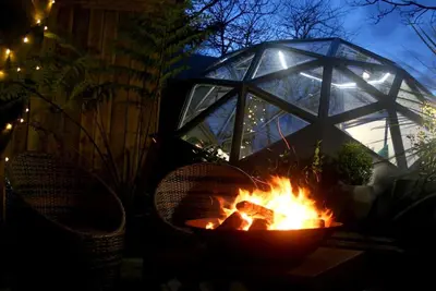 a fire pit with two chairs in front of it at night at Romance - Stargazing - Hot tub & sauna! in Camborne