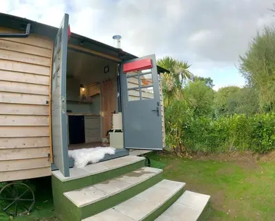 a tiny house with a door and a porch at Romantic Retreat - Luxury Shepherds Hut + Hot Tub! in Camborne