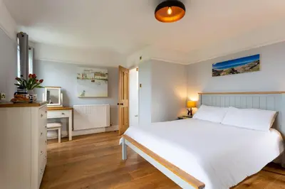 a bedroom with a large white bed and a desk at Millook View Farmhouse in Bude