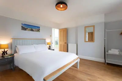a bedroom with a large white bed and a window at Millook View Farmhouse in Bude