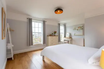 a bedroom with a white bed and a window at Millook View Farmhouse in Bude